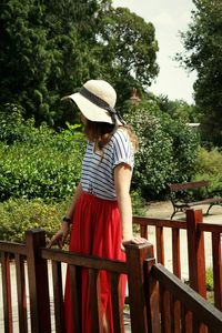Woman wearing hat standing on footbridge at park