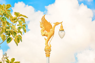 Low angle view of cross sculpture against sky