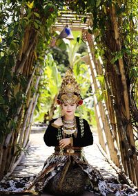 Portrait of young woman standing against plants