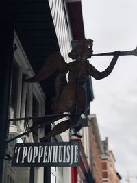 Low angle view of sign hanging on metal against sky