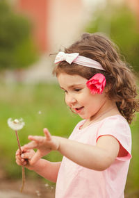 Cute girl holding tulip while standing outdoors