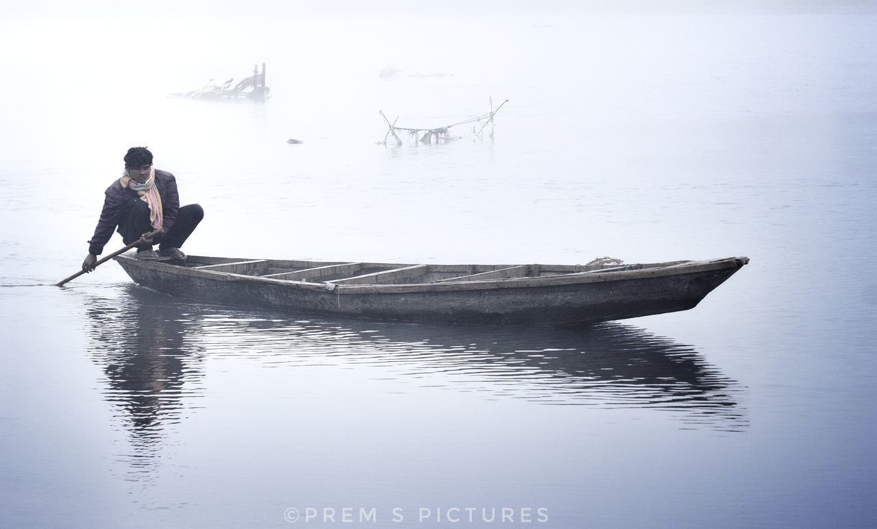 MAN ON LAKE AGAINST SKY