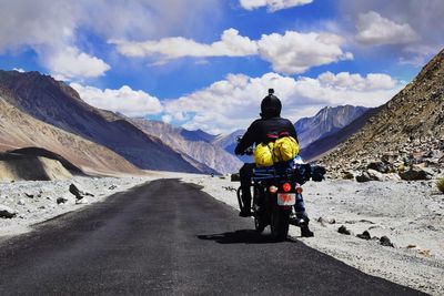 Rear view of man riding motorcycle on road against sky