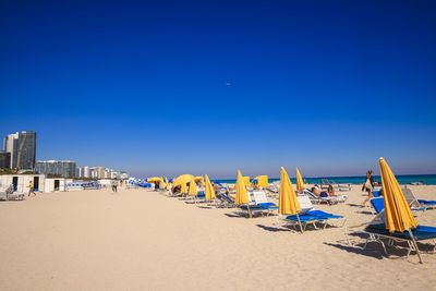 People at beach against clear blue sky at night