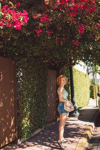 Portrait of young woman standing by tree