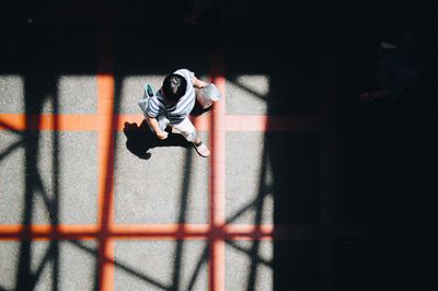 Directly above shot of woman walking on road during sunny day