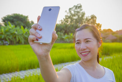 Portrait of smiling young woman holding smart phone outdoors