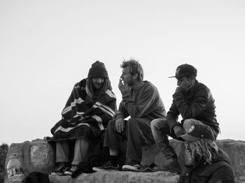 Low angle view of people sitting against clear sky