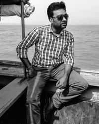 Young man wearing sunglasses standing against sea