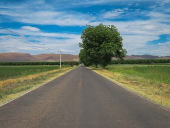 Road amidst field against sky