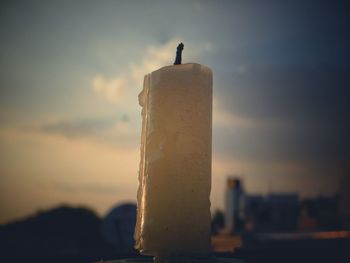 Close-up of bird perching on pole against sky