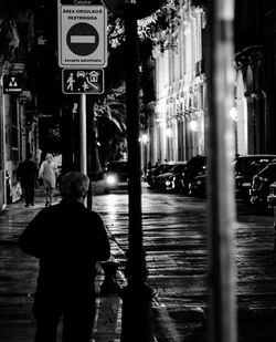 Rear view of man walking on road at night