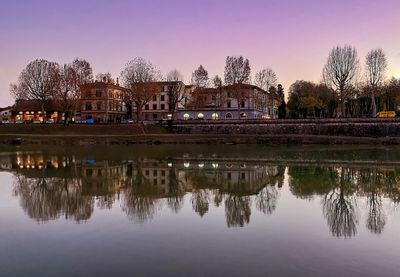 Reflection of building and trees in lake against sky