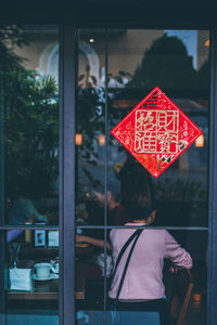 Rear view of man walking on road seen through glass window