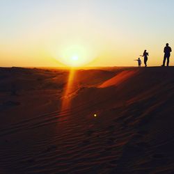 Silhouette people walking on desert against clear sky during sunset