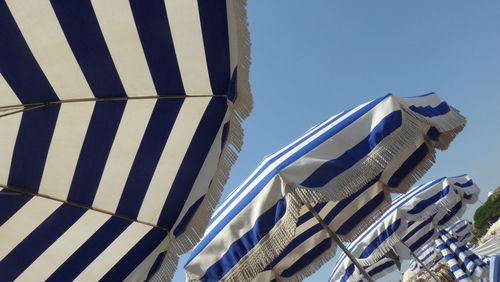 Low angle view of striped beach umbrellas against clear sky