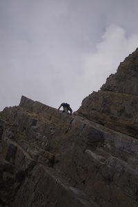 Low angle view of rock on cliff against sky