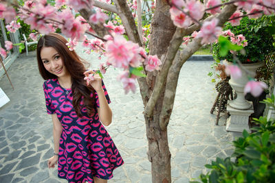 Low section of woman standing by pink flowering tree