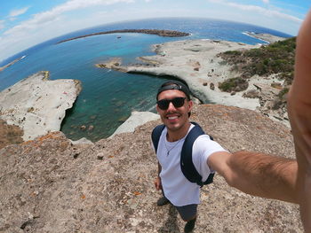 Portrait of young man wearing sunglasses at sea shore