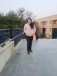 Portrait of smiling young woman standing against building