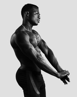 Side view of young man looking away against white background