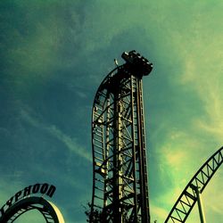 Low angle view of ferris wheel against cloudy sky