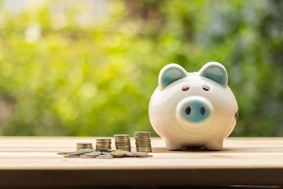 Close-up of coins with piggy bank on table