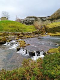 Scenic view of stream amidst rocks against sky