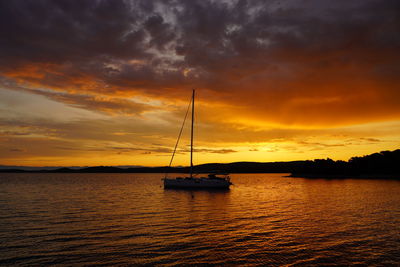 Sailboat on sea against romantic sky at sunset