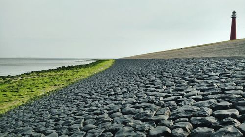 Pebbles on beach against clear sky