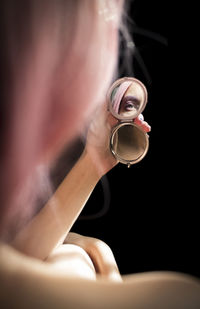 Rear view of woman looking in mirror against black background