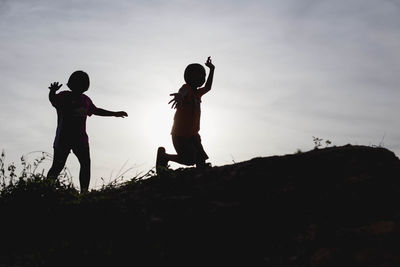 Silhouette friends standing on land against sky