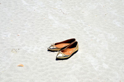 High angle view of flat shoes at sandy beach on sunny day