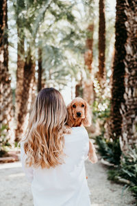 Rear view of woman with dog amidst trees at park