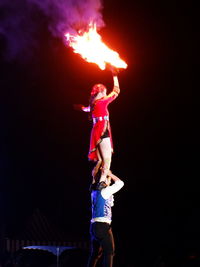 Full length of man and woman holding fire at night