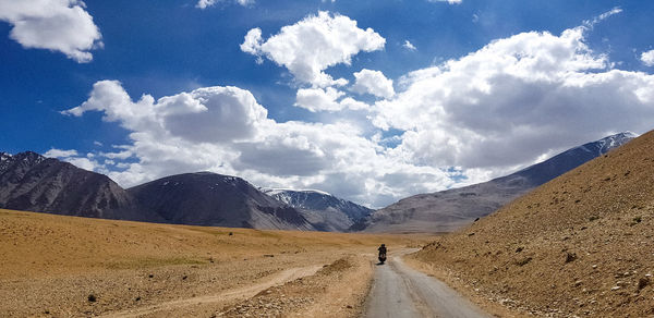 Man riding motor scooter on road amidst mountains against sky