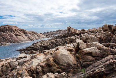 Rock formations on shore against sky