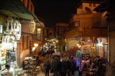 People on illuminated street amidst buildings at night