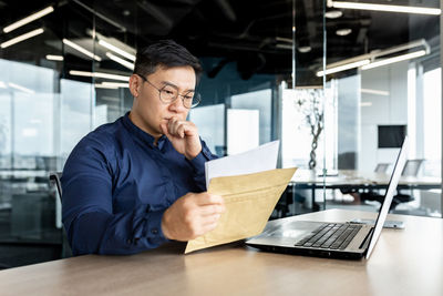 Side view of man using laptop on table