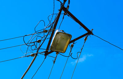 Low angle view of telephone pole against clear blue sky