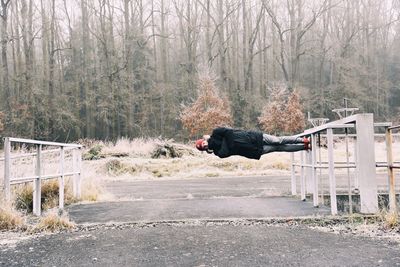 Full length of person standing on railing over street in forest