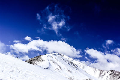 Low angle view of snowcapped mountains against blue sky