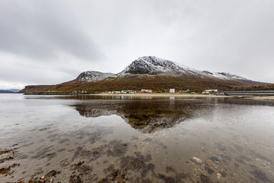 Scenic view of lake by snowcapped mountain against sky