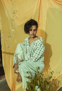 Young man looking away while sitting outdoors