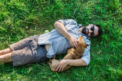 Top view of man and dog lying on green grass. attractive european man is hugging his dog.