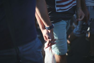 Close-up of men holding hands while walking outdoors