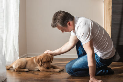 Young man playing with labrador retriever puppy at home. games with pets. animal friendship and care