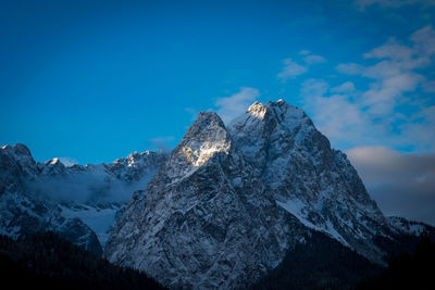 Low angle view of snow covered mountain against blue sky