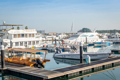 Sailboats moored at harbor against sky in city