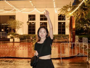 Portrait of young woman standing against building